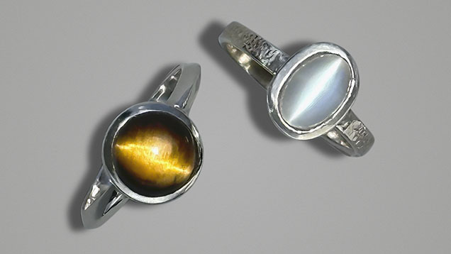 Figure 4. Stones with strong chatoyancy set in sterling silver rings: an 8 mm tiger’s-eye (left) and a 7 × 9 mm cat’s-eye moonstone (right). Courtesy of Jennifer Stone-Sundberg. Figure 4. Stones with strong chatoyancy set in sterling silver rings: an 8 mm tiger’s-eye (left) and a 7 × 9 mm cat’s-eye moonstone (right). Courtesy of Jennifer Stone-Sundberg.