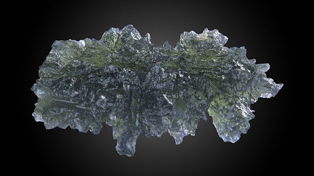 Figure 1. A true collector’s item, this 32.06 mm long ornate leaf-shaped olive green moldavite is from the Besednice strewn field in the Czech Republic. Possessing unbroken spires and undamaged surfaces, this pristine condition is rare. Photo by Maha Calderon.