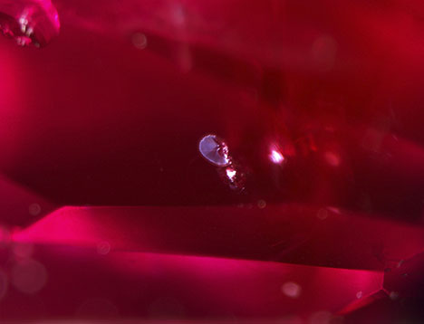 Figure 2. Heat-altered crystal inclusions surrounded by a discoid fracture, proving that the spinel underwent high-temperature treatment. Photomicrograph by Tsz Wing Lai; field of view 2.40 mm.