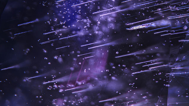 Numerous Rose channels with scattered zircon crystal inclusions in a 3.46 ct color-change sapphire. Photomicrograph by Michaela Damba; field of view 4.79 mm.