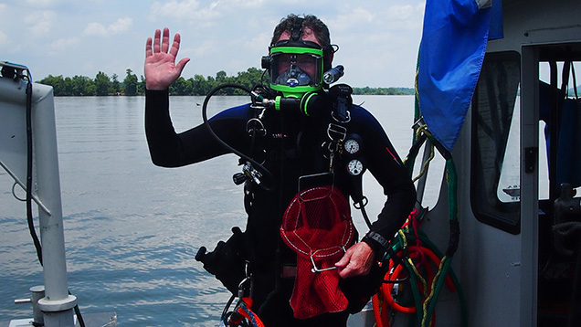 Waving diver with mussels on boat