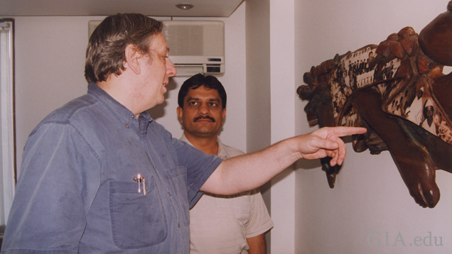 Two men look at a wall hanging.