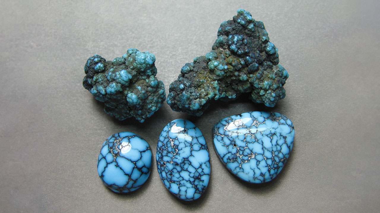 Figure 1. Extremely rare Black Web Gem mine turquoise nuggets and cabochons from Nevada. These pieces are natural with no treatments except for the backings added to the cabochons. The center oval is approximately 16 × 12 mm. Photo by Richard Shull; courtesy of Out of Our Mines.