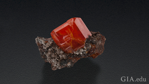 棒状の石基に囲まれている大きなレッドオレンジのウルフェナイトの結晶。