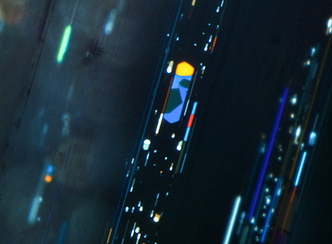 Iridescent platy voids in phenakite under oblique fiber-optic illumination.
