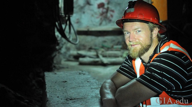 Man in a hard hat sits in an underground emerald mine.