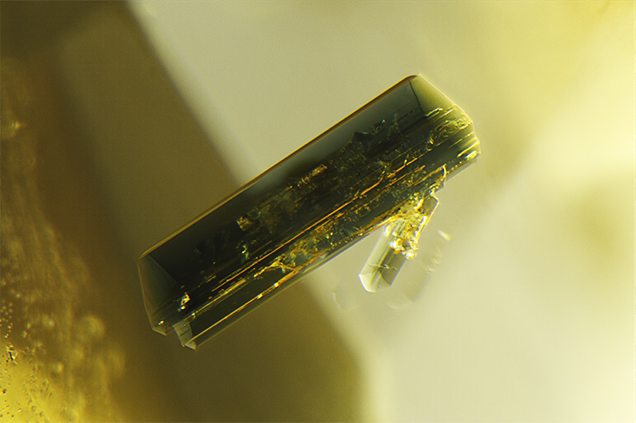 Euhedral pargasite crystal in yellow sapphire. Euhedral pargasite crystal in yellow sapphire.