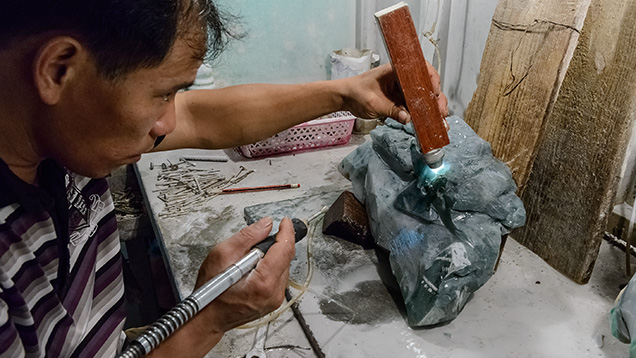 Artist in initial stages of carving rough jadeite Artist in initial stages of carving rough jadeite