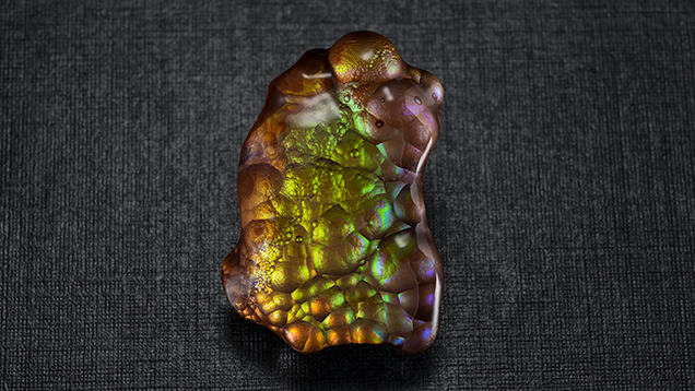 A freeform piece of fire agate shows brown, yellow, orange, green and purple colors.