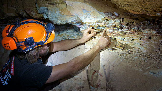 Man pointing to opal vein in underground mine Man pointing to opal vein in underground mine