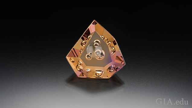A triangular shaped piece of ametrine (yellow and purple) with “bubbles” of internal carvings. A triangular shaped piece of ametrine (yellow and purple) with “bubbles” of internal carvings.