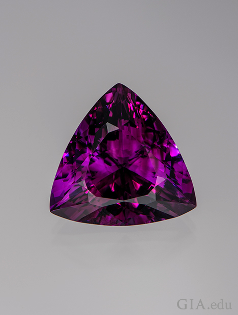 A triangle shaped piece of purple-red amethyst.