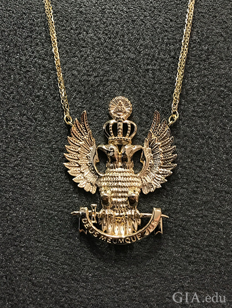 吊坠的造型是两只背靠背坐着、展翅的鹰，它们头上有一顶皇冠。
