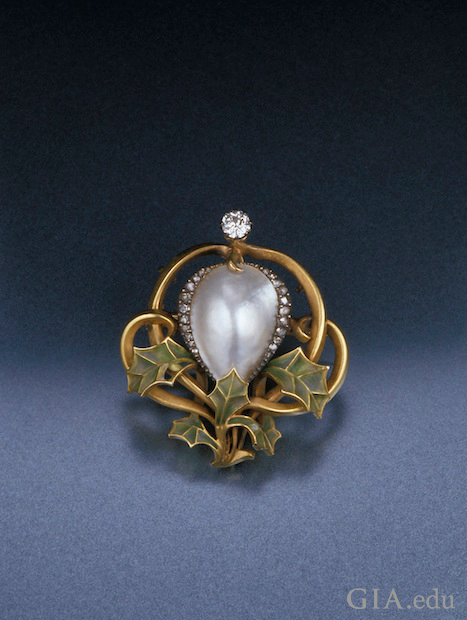 A blister pearl in the center, framed by diamonds and framed on the bottom with green enamel leaves. A blister pearl in the center, framed by diamonds and framed on the bottom with green enamel leaves.