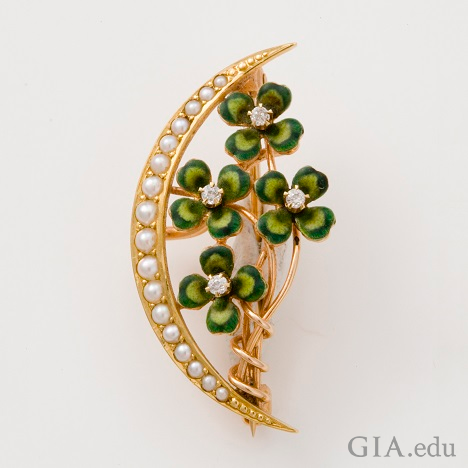 Four clover leaves climb up a branch – framed on the left side with a crescent of pearls. Four clover leaves climb up a branch – framed on the left side with a crescent of pearls.