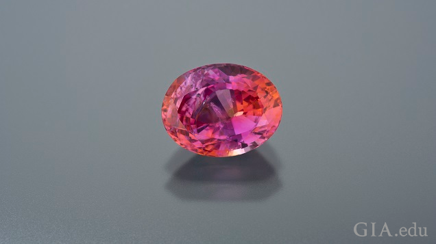 A band of pink in the center is bordered by orange on each side in this oval Padparadscha sapphire. A band of pink in the center is bordered by orange on each side in this oval Padparadscha sapphire.