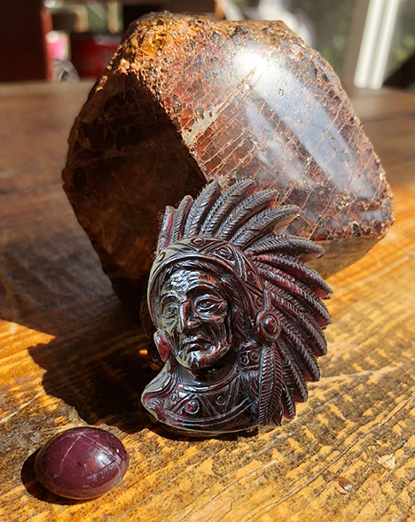 Figure 2. Vietnamese garnet from Phu Tho displays a medium dark brown-red, translucent to opaque appearance. The polished octahedral crystal weighs 450 g, the carving weighs 234 g, and the four-rayed star garnet weighs 26 ct. Photo by Pham Minh Tien. Figure 2. Vietnamese garnet from Phu Tho displays a medium dark brown-red, translucent to opaque appearance. The polished octahedral crystal weighs 450 g, the carving weighs 234 g, and the four-rayed star garnet weighs 26 ct. Photo by Pham Minh Tien.