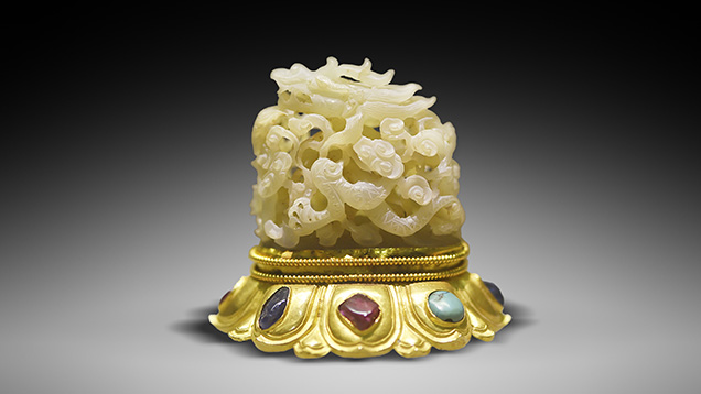 White nephrite carved jade dragon sits on a gem-inlaid gold base. White nephrite carved jade dragon sits on a gem-inlaid gold base.