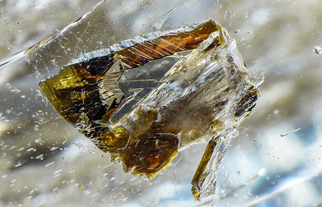 Strong brownish orange and yellow dichroism can be seen in this phlogopite mica crystal inclusion. Strong brownish orange and yellow dichroism can be seen in this phlogopite mica crystal inclusion.