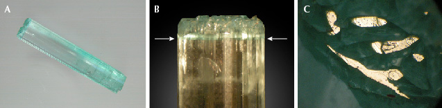 Figure 15. A: Sample 15 (37.4 mm in length), an emerald crystal with color zoning; at one end, the sample reveals a continuous rim surrounding growth areas ending in small basal faces. B: Growth and color zoning (arrows) of the crystal along the c-axis. C: Areas of the rim and small columns inside the rim with planes parallel to the basal pinacoid appear bright in reflected light, viewed parallel to the c-axis. Photos by K. Schmetzer; field of view 3.6 mm (C). Figure 15. A: Sample 15 (37.4 mm in length), an emerald crystal with color zoning; at one end, the sample reveals a continuous rim surrounding growth areas ending in small basal faces. B: Growth and color zoning (arrows) of the crystal along the c-axis. C: Areas of the rim and small columns inside the rim with planes parallel to the basal pinacoid appear bright in reflected light, viewed parallel to the c-axis. Photos by K. Schmetzer; field of view 3.6 mm (C).