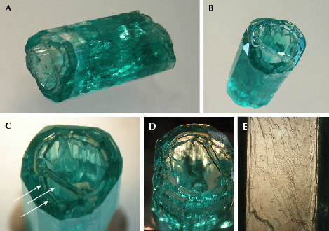 Figure 18. A and B: Sample 18 (19.6 mm in length), an emerald crystal developed in the form of a deep cup. B and C: Openings at one end are developed in the basal pinacoid but also in the largest p dipyramid (arrows); within the cup, a framework of irregularly shaped thin emerald walls is present. D: The crystal faces at the inner surface of the wall are oriented parallel to the outer prism faces. E: Growth steps on the surface of an m prism. Photos by K. Schmetzer; fields of view 11.5 mm (D, vertical) and 5.1 mm (E). Figure 18. A and B: Sample 18 (19.6 mm in length), an emerald crystal developed in the form of a deep cup. B and C: Openings at one end are developed in the basal pinacoid but also in the largest p dipyramid (arrows); within the cup, a framework of irregularly shaped thin emerald walls is present. D: The crystal faces at the inner surface of the wall are oriented parallel to the outer prism faces. E: Growth steps on the surface of an m prism. Photos by K. Schmetzer; fields of view 11.5 mm (D, vertical) and 5.1 mm (E).