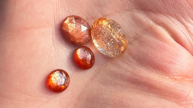 Figure 7. Sunstone with schiller from Madras, India, demonstrating the variety available in terms of depth of color and transparency. Note the bicolor nature of the larger faceted gem (13 × 17 mm), which exhibits a blue tinge at the top and bottom. Photo by Jennifer Stone-Sundberg; courtesy of Sami Gems & Jewellers. Figure 7. Sunstone with schiller from Madras, India, demonstrating the variety available in terms of depth of color and transparency. Note the bicolor nature of the larger faceted gem (13 × 17 mm), which exhibits a blue tinge at the top and bottom. Photo by Jennifer Stone-Sundberg; courtesy of Sami Gems & Jewellers.
