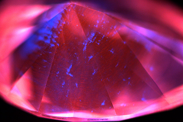Figure 2. Representative deep-UV fluorescence image of a 2.90 ct CVD diamond from Plasmability, collected using the DiamondView. The image is dominated by red–orange fluorescence from NV0 centers, a common feature for untreated CVD laboratory-grown diamonds, along with irregular blue fluorescing dislocation bundles. No growth layers were observed, indicating that it was produced through a single uninterrupted growth cycle. Image by Madelyn Dragone. Figure 2. Representative deep-UV fluorescence image of a 2.90 ct CVD diamond from Plasmability, collected using the DiamondView. The image is dominated by red–orange fluorescence from NV0 centers, a common feature for untreated CVD laboratory-grown diamonds, along with irregular blue fluorescing dislocation bundles. No growth layers were observed, indicating that it was produced through a single uninterrupted growth cycle. Image by Madelyn Dragone.