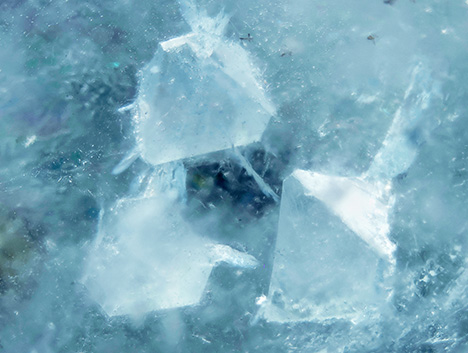 Figure 2. Close-up of three fluorite crystals in aquamarine. Photomicrograph by Harold Moritz; field of view 15 mm. Figure 2. Close-up of three fluorite crystals in aquamarine. Photomicrograph by Harold Moritz; field of view 15 mm.