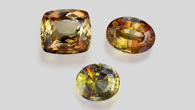 Figure 6. Gem-quality andalusite weighing 23.75 ct (top left), 14.41 ct (top right), and 17.56 ct (bottom). Photo by Robert Weldon; courtesy of the Dr. Edward J. Gübelin Collection (top) and Pala International (bottom). Figure 6. Gem-quality andalusite weighing 23.75 ct (top left), 14.41 ct (top right), and 17.56 ct (bottom). Photo by Robert Weldon; courtesy of the Dr. Edward J. Gübelin Collection (top) and Pala International (bottom).
