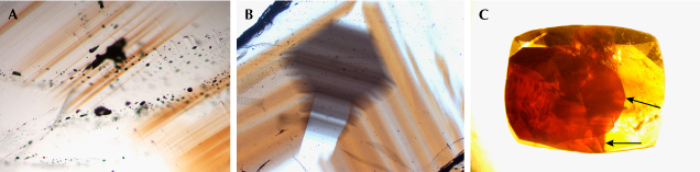 Figure 9. Color heterogeneity of cassiterite from Yunling. A: Fine brownish yellow color bands. B: Gray color domain. C: The red color observed in the red sample, viewed in immersion, appears to be confined to two fractures and distributed within planes (indicated by arrows). This distribution suggests that the red color is caused by iron oxide staining within the fractures. Photomicrographs by Wenqing Huang; fields of view 1.2 mm (A), 3.9 mm (B), and 10 mm (C). Figure 9. Color heterogeneity of cassiterite from Yunling. A: Fine brownish yellow color bands. B: Gray color domain. C: The red color observed in the red sample, viewed in immersion, appears to be confined to two fractures and distributed within planes (indicated by arrows). This distribution suggests that the red color is caused by iron oxide staining within the fractures. Photomicrographs by Wenqing Huang; fields of view 1.2 mm (A), 3.9 mm (B), and 10 mm (C).