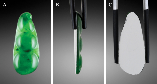 Figure 1. A: Face-up view of the 23.71 × 9.67 × 2.59 mm jade carving. B: The profile view shows the thickness of the thin film lining. C: The back of the carving shows the reflective metallic luster of the film. Photos by Diego Sanchez. Figure 1. A: Face-up view of the 23.71 × 9.67 × 2.59 mm jade carving. B: The profile view shows the thickness of the thin film lining. C: The back of the carving shows the reflective metallic luster of the film. Photos by Diego Sanchez.