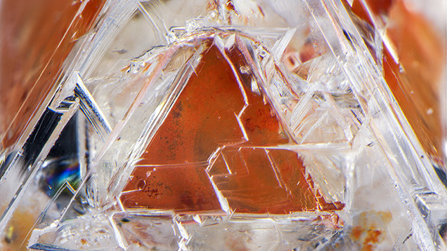 Figure 2. One of eight triangular limonitic faces in the 2.22 ct diamond crystal containing a phantom. Photomicrograph by Nathan Renfro; field of view 4.78 mm. Figure 2. One of eight triangular limonitic faces in the 2.22 ct diamond crystal containing a phantom. Photomicrograph by Nathan Renfro; field of view 4.78 mm.