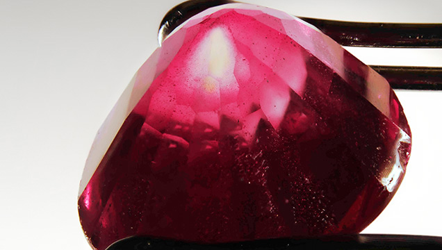 A portion of the near-colorless corundum seed is revealed in an area where the synthetic ruby overgrowth was cut away.