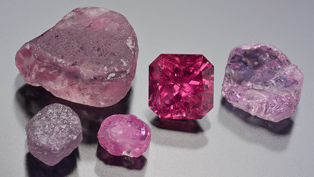 The 1.70 ct Montana ruby alongside rough corundum reference samples