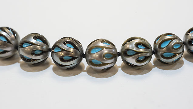 Figure 13. The Galatea Pearl uses synthetic turquoise or other gem material as a bead nucleus to produce a bead cultured Tahitian pearl. Later the pearl is hand carved to display the beautiful blue color of the turquoise, highlighting the contrast against the dark nacre. The pearls in this necklace are about 10.5 mm in diameter. Photo by Kevin Schumacher. Figure 13. The Galatea Pearl uses synthetic turquoise or other gem material as a bead nucleus to produce a bead cultured Tahitian pearl. Later the pearl is hand carved to display the beautiful blue color of the turquoise, highlighting the contrast against the dark nacre. The pearls in this necklace are about 10.5 mm in diameter. Photo by Kevin Schumacher.