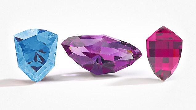 Figure 2. Gemstone cutters in Kenya, Malawi, and Zambia developed cuts to represent their countries in Virtu Gem’s National Gem Cut Course. Left to right: the Kenya Cheetah Head, Zambia Eagle, and Malawi Mbuna Fish cuts in aquamarine, amethyst, and rhodolite garnet. Photo courtesy of Virtu Gem.