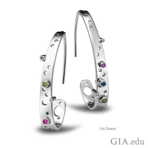 Front view of platinum “J” hoop earrings designed by Erik Stewart, featuring a variety of small, bezel-set colored stones and circles of different sizes that use negative space as a design motif. Front view of platinum “J” hoop earrings designed by Erik Stewart, featuring a variety of small, bezel-set colored stones and circles of different sizes that use negative space as a design motif.