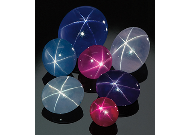 A group of star sapphires, fancy star sapphires and one star ruby on a black background A group of star sapphires, fancy star sapphires and one star ruby on a black background