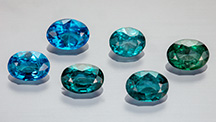 Figure 1. Suite of faceted nickel-diffused spinel (0.67–1.01 ct) showing a range of color from blue to bluish green. Photo by Aaron Palke and Diego Sanchez. Figure 1. Suite of faceted nickel-diffused spinel (0.67–1.01 ct) showing a range of color from blue to bluish green. Photo by Aaron Palke and Diego Sanchez.
