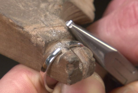 Close-up view showing a platinum band with a piece removed from the ring shank in preparation for sizing it down Close-up view showing a platinum band with a piece removed from the ring shank in preparation for sizing it down