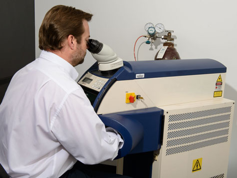 Practitioner seated at the laser welder, welding a platinum ring Practitioner seated at the laser welder, welding a platinum ring