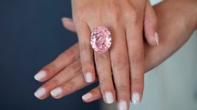The 59.60 ct mixed-cut oval CTF Pink star diamond is displayed on a woman’s hands. It is wider than her ring finger.