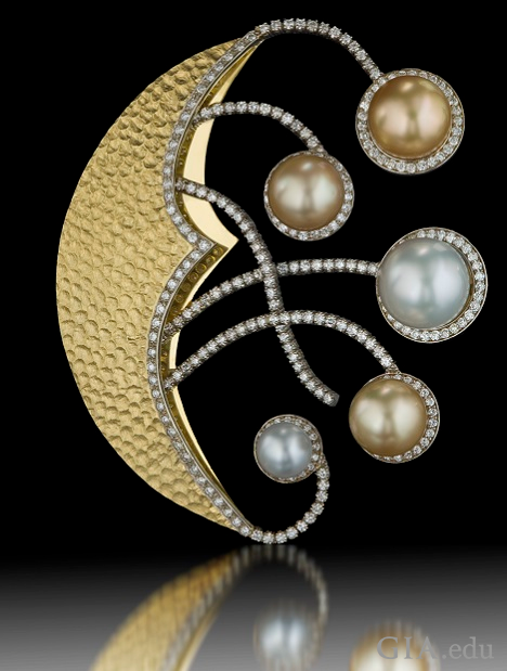 A crescent moon-shaped pin with “arms” that reach out from its center. Each “arm” holds a pearl at the end. A crescent moon-shaped pin with “arms” that reach out from its center. Each “arm” holds a pearl at the end.