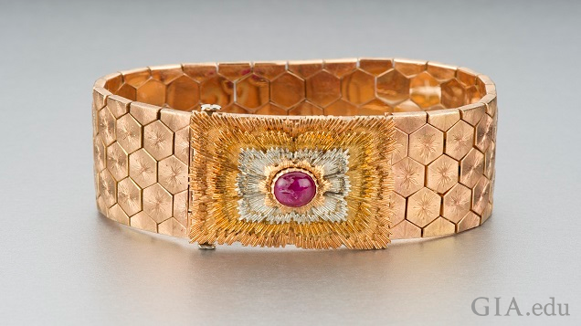 Wide rose gold patterned bracelet features a ruby cabochon. Wide rose gold patterned bracelet features a ruby cabochon.