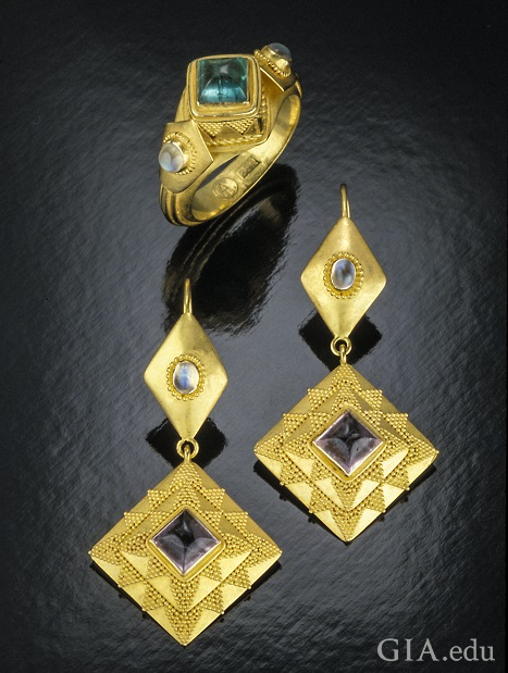 Triangle-shaped pieces with a tourmaline center drop from a diamond-shaped top with a moonstone center. Triangle-shaped pieces with a tourmaline center drop from a diamond-shaped top with a moonstone center.