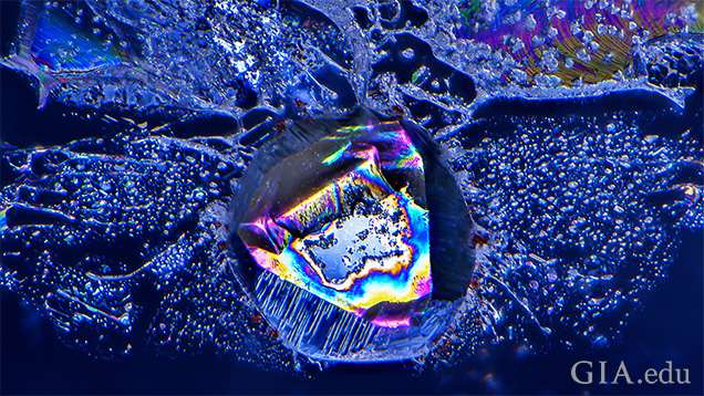 A negative crystal filled with carbonate and analcime minerals shows colorful thin-film interference in this untreated sapphire from Yogo Gulch, Montana. Field of view 1.28 mm. A negative crystal filled with carbonate and analcime minerals shows colorful thin-film interference in this untreated sapphire from Yogo Gulch, Montana. Field of view 1.28 mm.