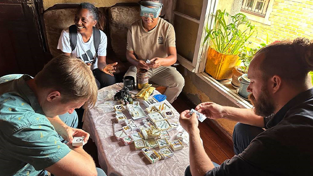 Four people sitting around a table examining gems. Four people sitting around a table examining gems.